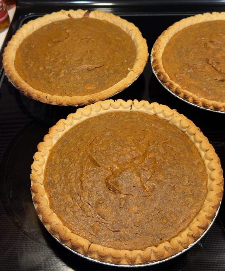 Three freshly baked sweet potato pies cooling on a stovetop on Thanksgiving eve